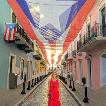 Anna in front of a large Puerto Rican flag hanging above an entire street after her relocation