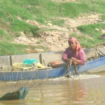 A villager working out of her canoe by the water.