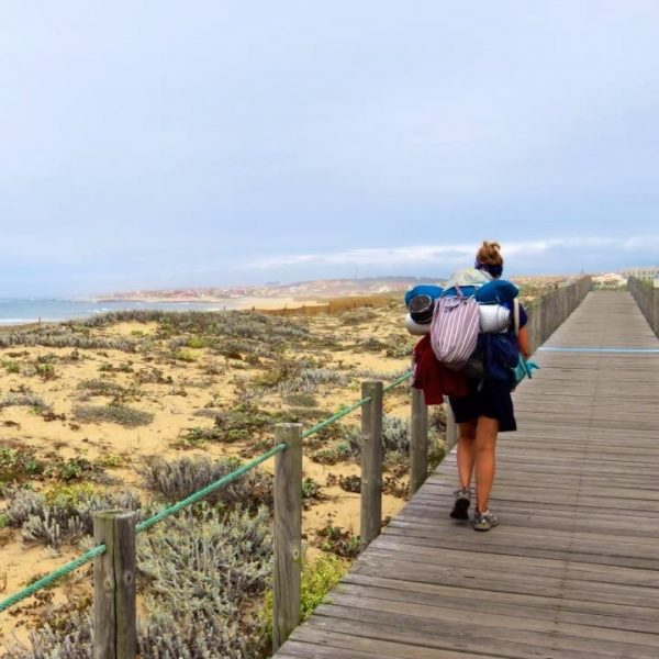 Olivia walking along a boardwalk next to beach dunes on her spiritual journey