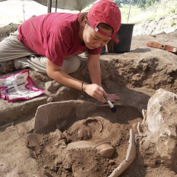 A photo of Jiye brushing off an artifact at a dig site.