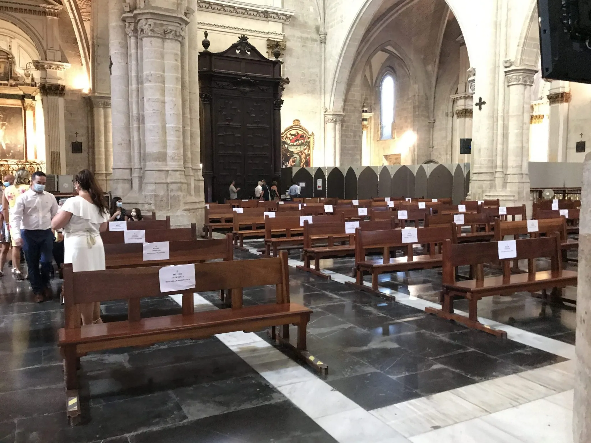 An image of church pews with social distancing signs as people start traveling again.
