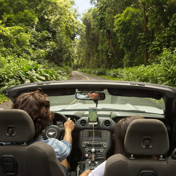 Two people driving in a convertible while on the Shaka Guided Tour