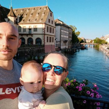 Kristen and her husband and baby in front of a beautiful canal.