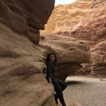 Alana posing on the side of a red canyon in Israel, which Alana visited during her Hillel trip